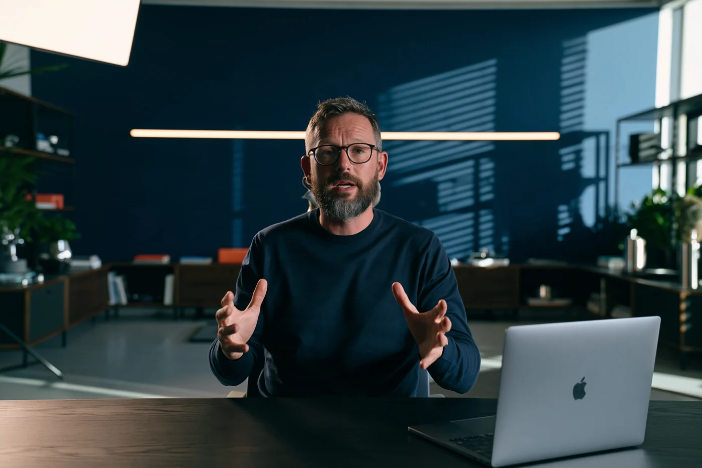 Tech presenter speaking to camera at his desk